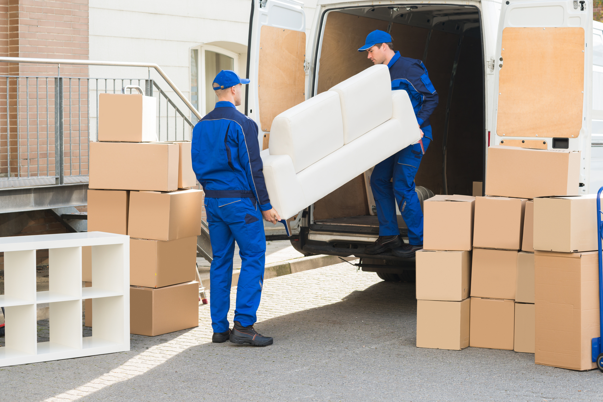Men in Blue Uniforms Carrying a Couch Into a Van